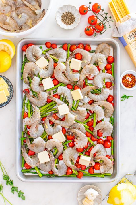 Veggies, shrimp, and butter on a sheet pan to roast.